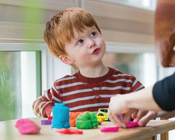 Boy playing with colorful modeling clay indoors