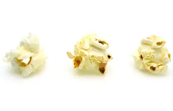 Three popped corn pieces on plain white backdrop