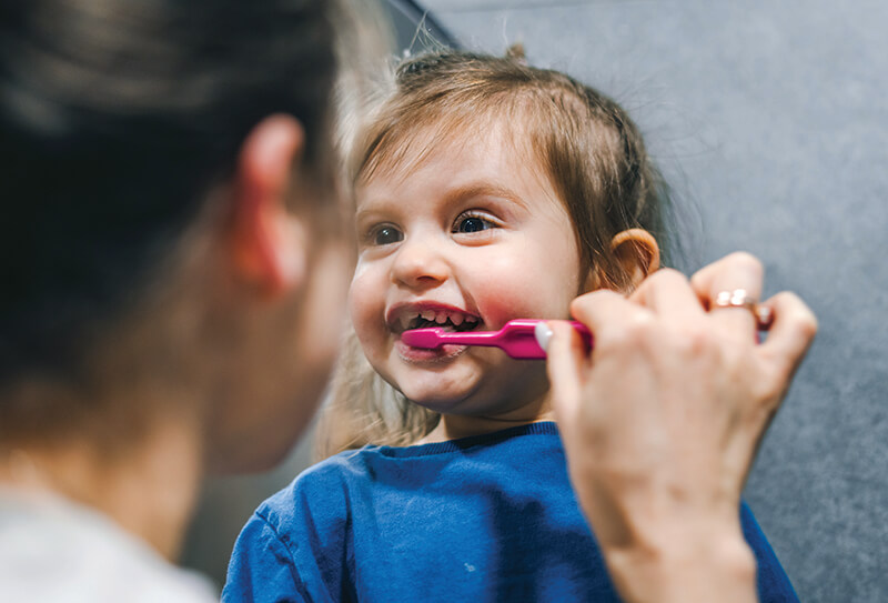 Young girl smiling while brushing teeth